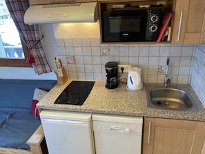 Una cocina compacta con lavavajillas Bosch, lavavajillas Siemens, microondas, cafetera y un lavabo.