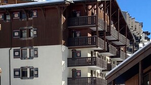 Un edificio de varios pisos con balcones y un techo cubierto de nieve.