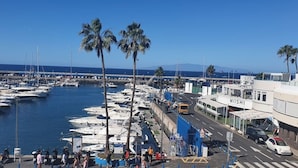 Un port de plaisance avec des bateaux amarrés, une route avec des véhicules et des bâtiments, dont l’un est identifié par l’inscription « MIISHI ».