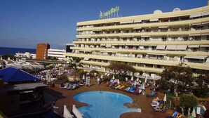 Un hôtel doté d’une piscine, de plusieurs balcons et offrant une vue sur l’océan.