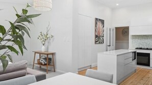 Une cuisine moderne avec des meubles blancs, un îlot central et un luminaire suspendu.