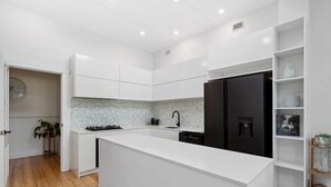 Une cuisine moderne avec des meubles blancs, un réfrigérateur noir et un dosseret de comptoir en granit.