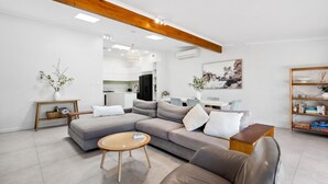 Un salon moderne avec un canapé d’angle, une table basse ronde et un fauteuil en cuir.