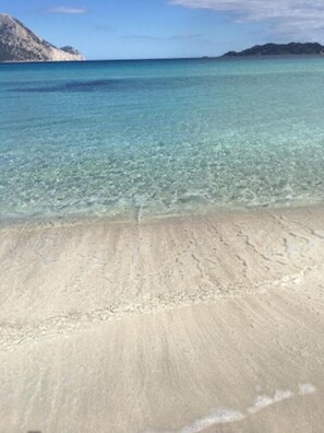 A beach with clear shallow waters and a sandy shore.