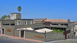 Un edificio moderno con techo plano, paneles solares y una palmera.