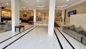Eine Hotelhalle mit Marmorboden, einer Rezeption, Sofas und einer Treppe zu den oberen Etagen.