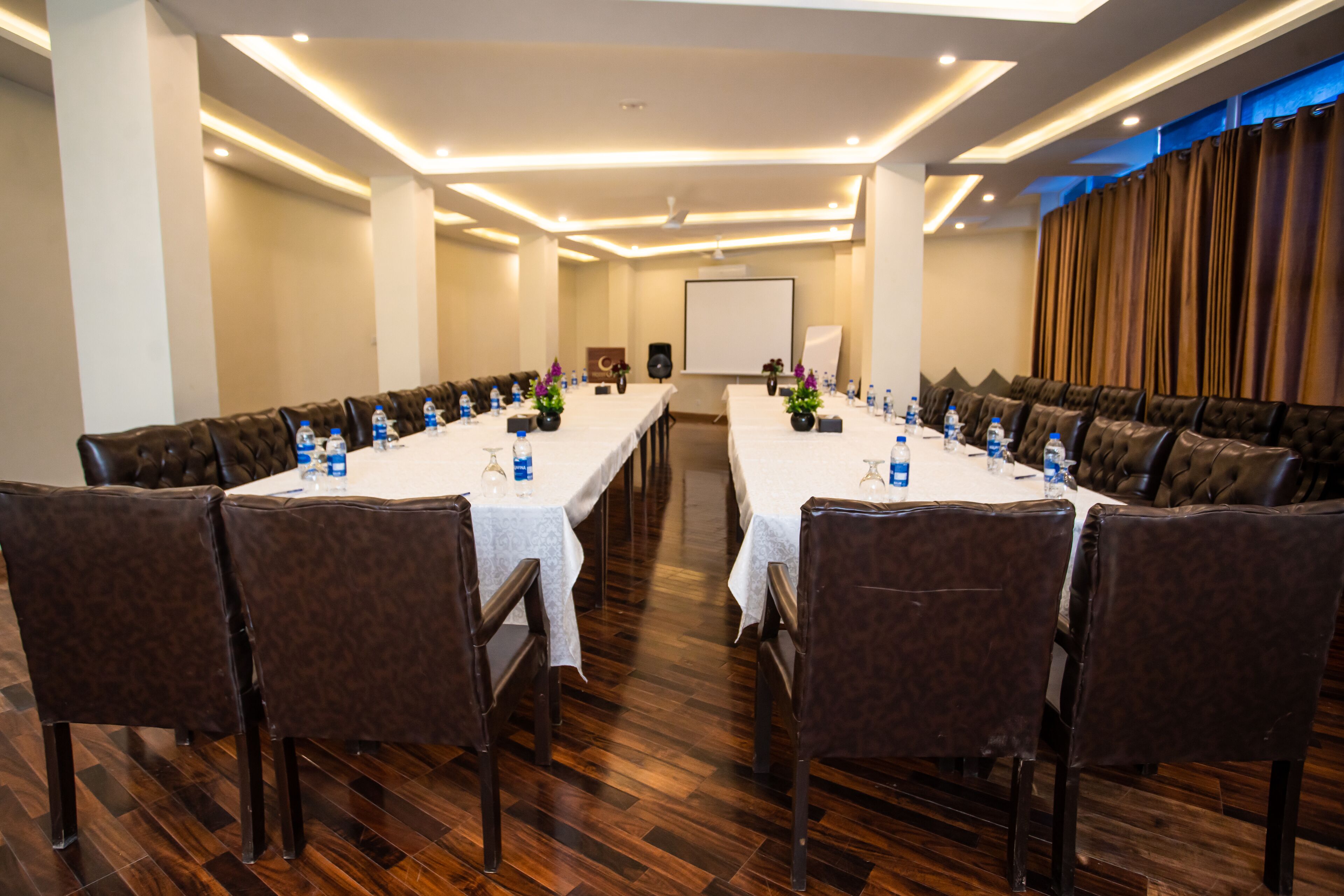 A conference room with long tables, brown leather chairs, and a whiteboard.