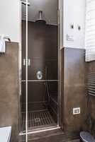 Een moderne badkamer met een glazen douchecabine, toilet en wastafel.