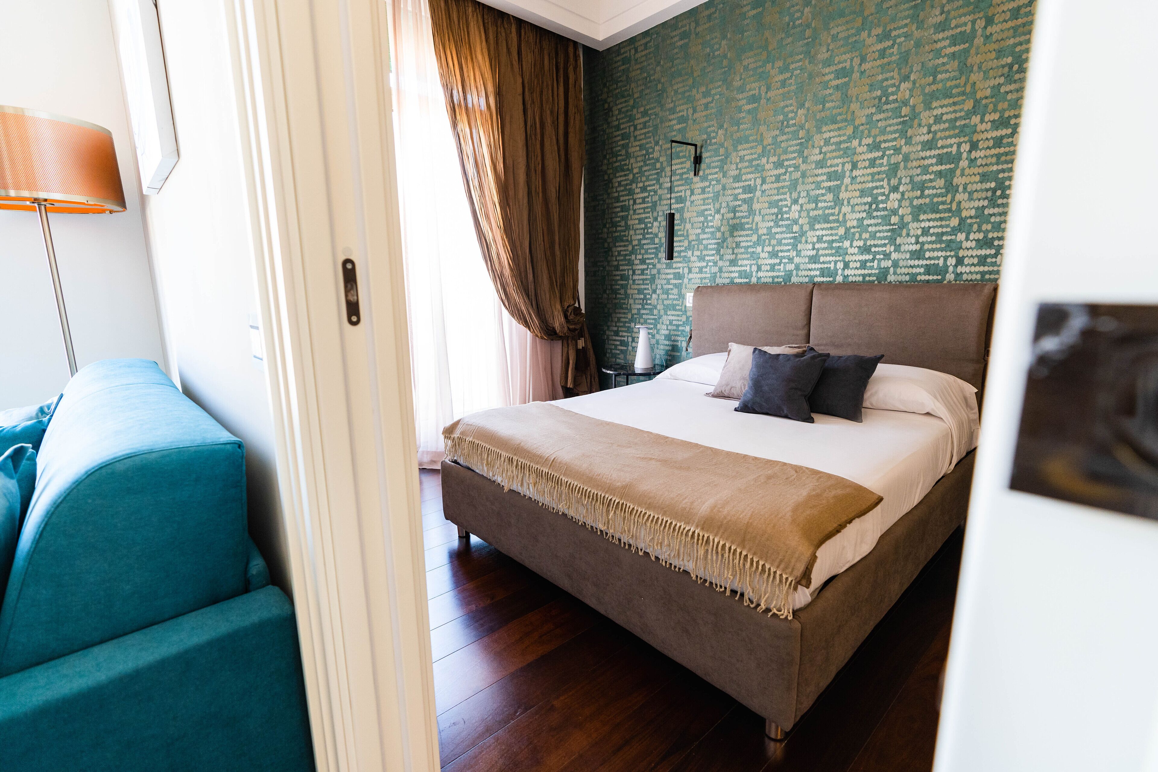 A bedroom with a large bed, a nightstand, a lamp, and a blue chair.