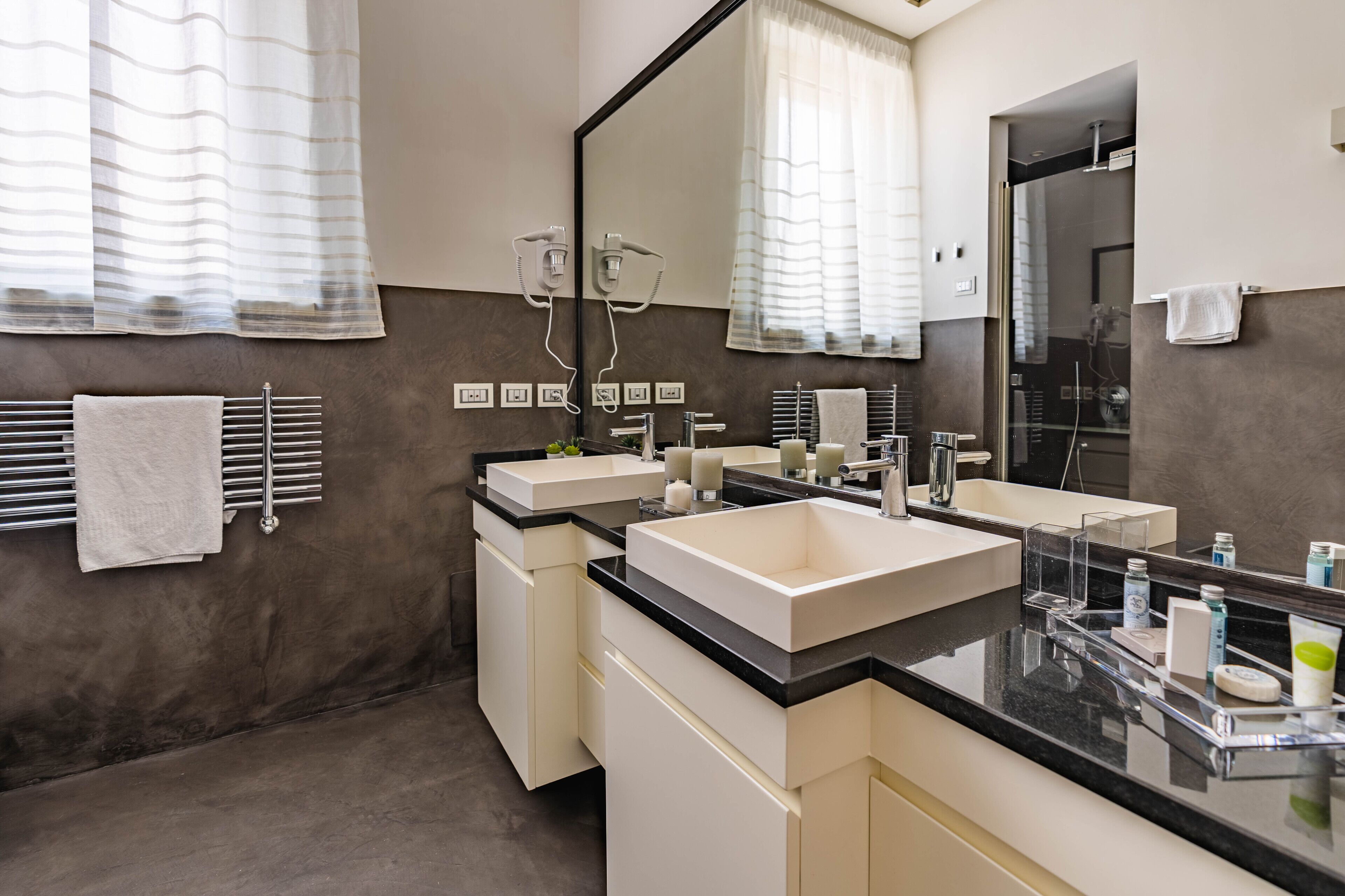 A modern bathroom with two sinks, a large mirror, and a glass shower enclosure.