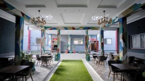 Un comedor moderno con una alfombra verde central, varias mesas y sillas.