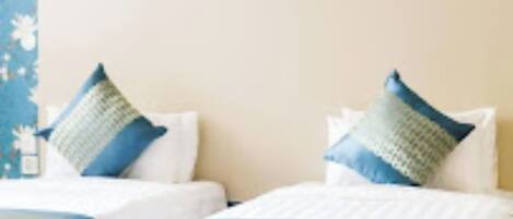 Une chambre d’hôtel avec deux lits, chacun étant équipé de draps blancs et d’oreillers bleus.