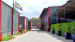 Un edificio con fachada roja y gris, un paseo techado y macetas a lo largo del sendero.