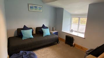 Een slaapkamer met een bed, een radiator, een raam en een foto aan de muur.