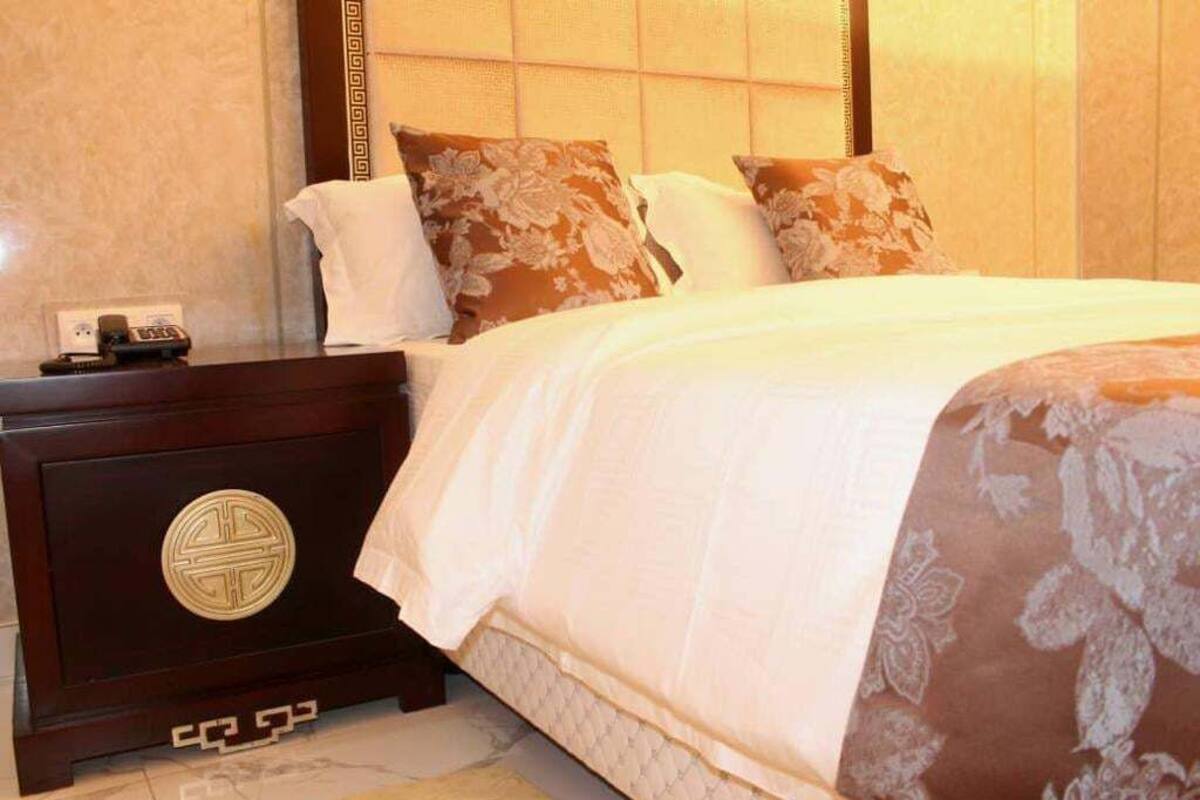 Una habitación de hotel con una cama, una mesita de noche y un teléfono instalado en la pared.