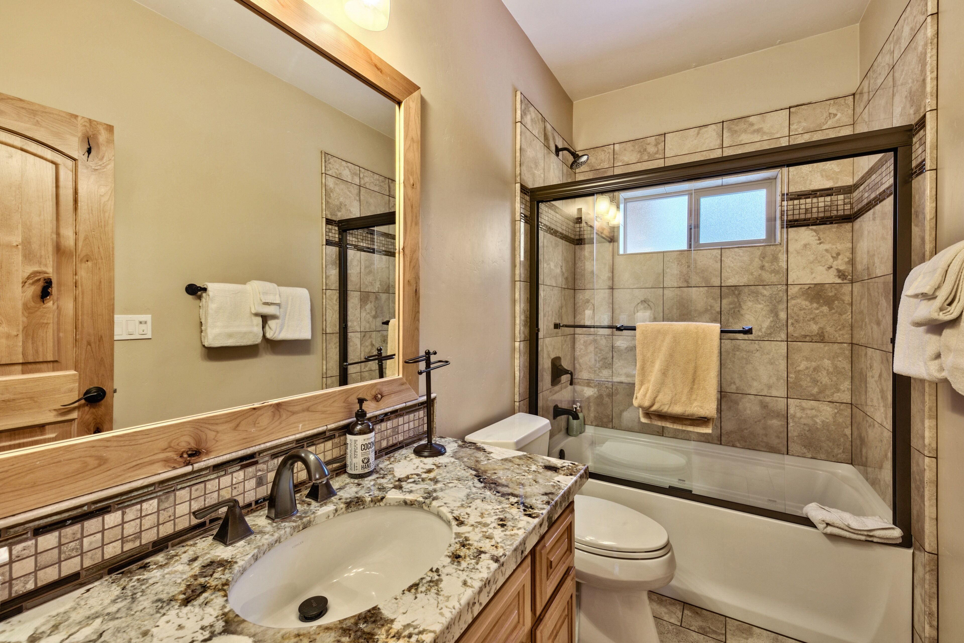Baño con lavamanos, inodoro y zona de ducha.