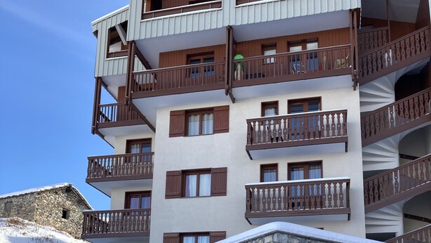 Un hotel a più piani con balconi, facciata in pietra e un paesaggio innevato.