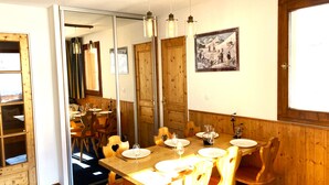 Zona pranzo con mobili in legno, un tavolo imbandito per quattro persone e un quadro appeso al muro.