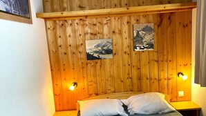 Una stanza con una testiera di legno, due lampade ai comodini, un letto con biancheria da letto bianca e due quadri appesi al muro.