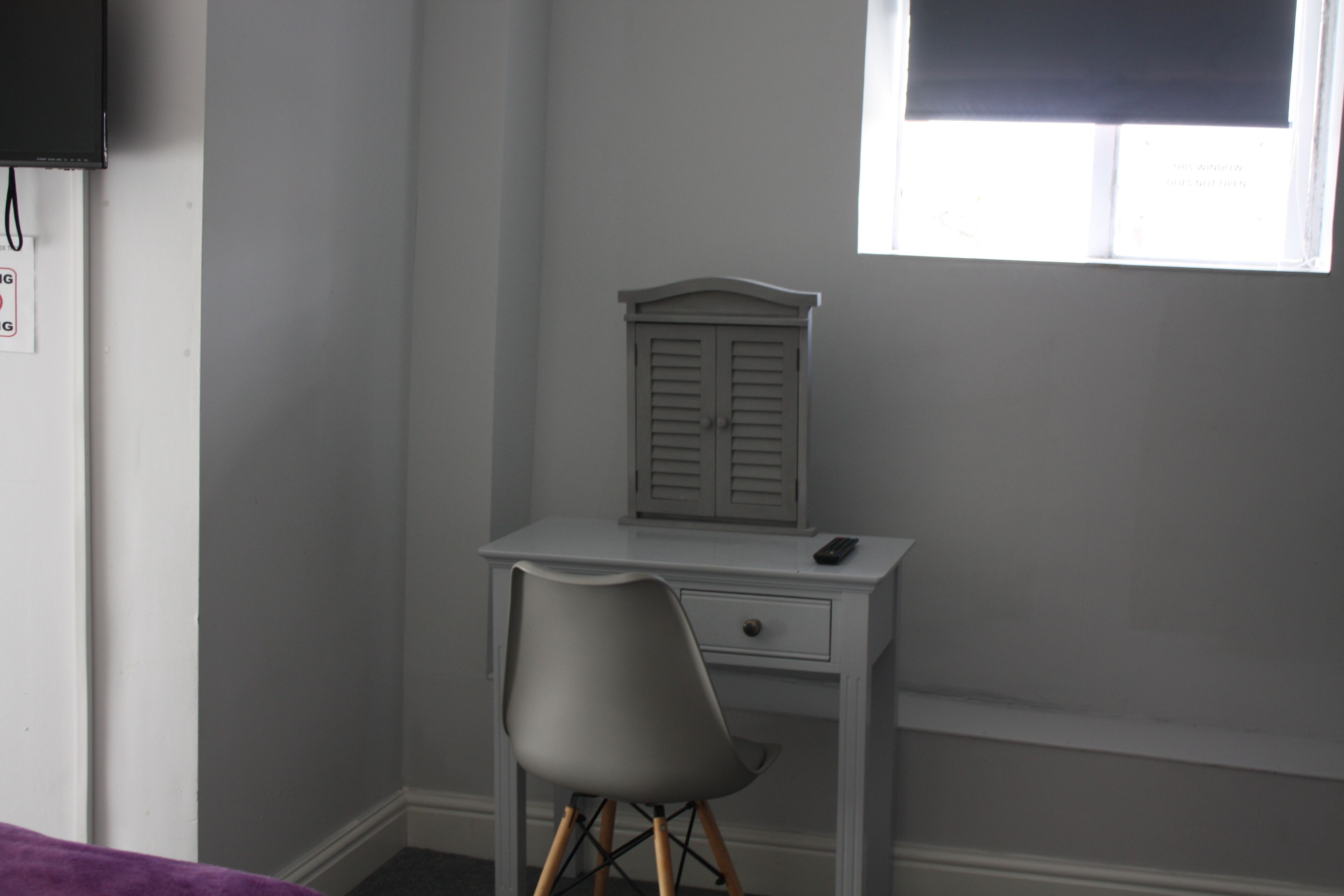 A small, white desk with a chair and a small cabinet.
