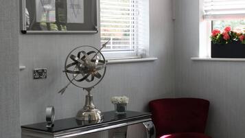 Ein Zimmer mit einem roten Sessel, einem Schreibtisch mit Globus und einem Fenster mit Jalousien.