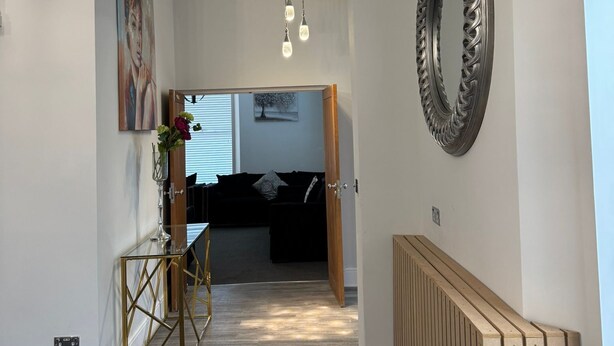 Un couloir avec un radiateur, un miroir et un tableau accroché au mur.