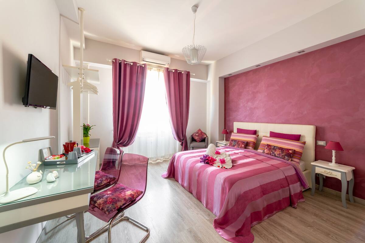 Quarto moderno com cama, escrivaninha, cadeira e televisão.