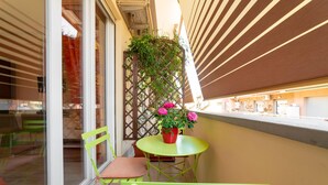 A balcony with a green chair, a small round table, and a potted plant with pink flowers. - B&B La Maison de Jo (Rome)