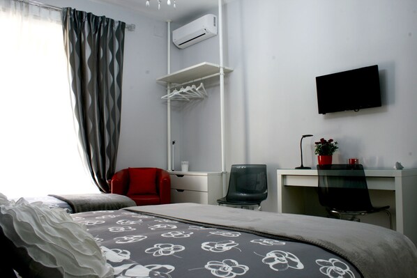 Una habitación de hotel con cama, escritorio, silla, televisor y armario.
