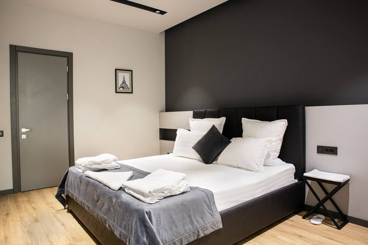 Ein modernes Schlafzimmer mit einem großen Bett, einem Nachttisch und einer Tür.