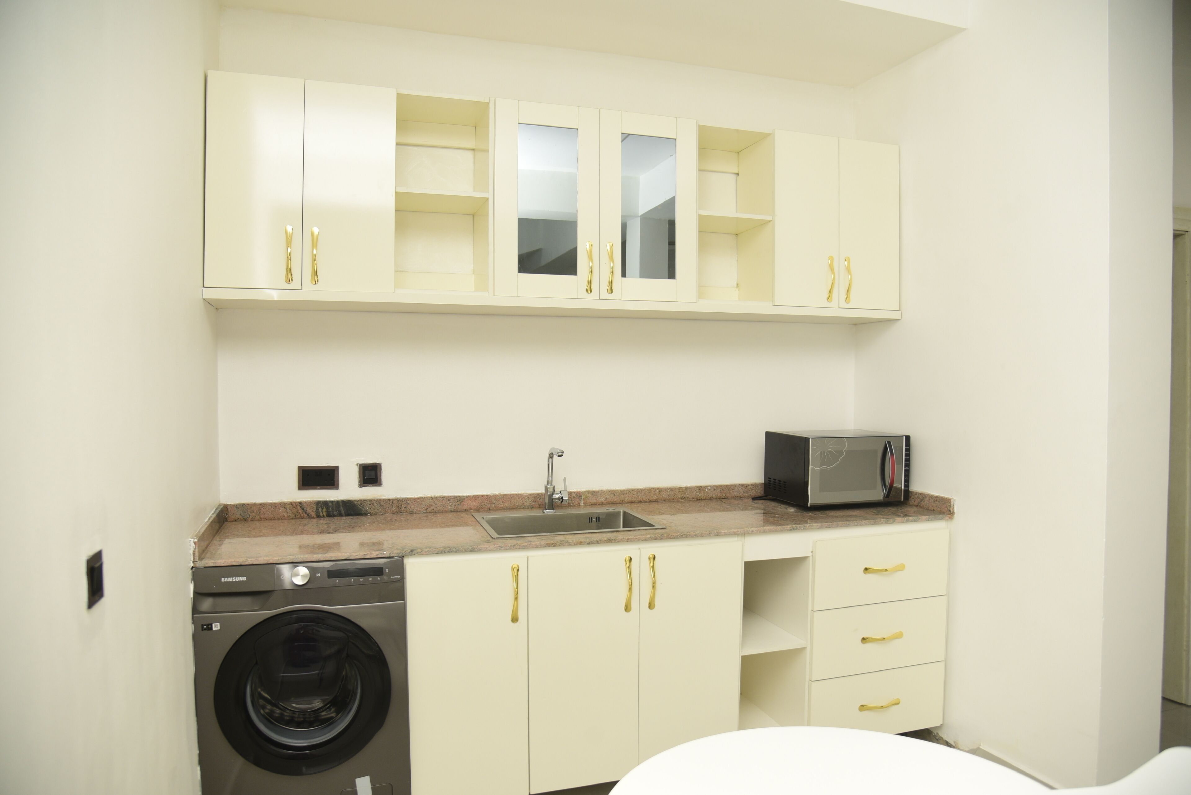 Cocina compacta con lavadora, microondas y lavamanos.