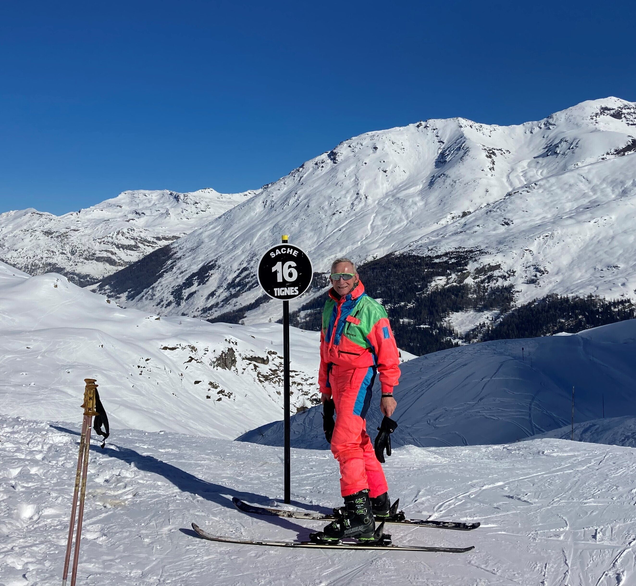 Una persona parada sobre esquíes, con un cartel que dice "SACHE 16 TIGNES" al fondo.