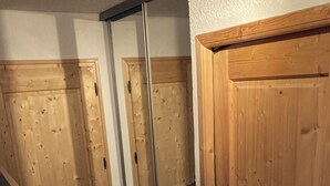 A wooden door with a metal handle, a wooden staircase, and a tiled floor. - Tignes, Val Claret - at the centre of the Tignes and Val d'Isere ski area. (Tignes)