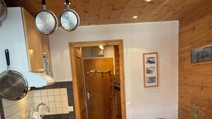 A compact kitchen with wooden cabinets, a sink, and a dining area with a table. - Tignes, Val Claret - at the centre of the Tignes and Val d'Isere ski area. (Tignes)