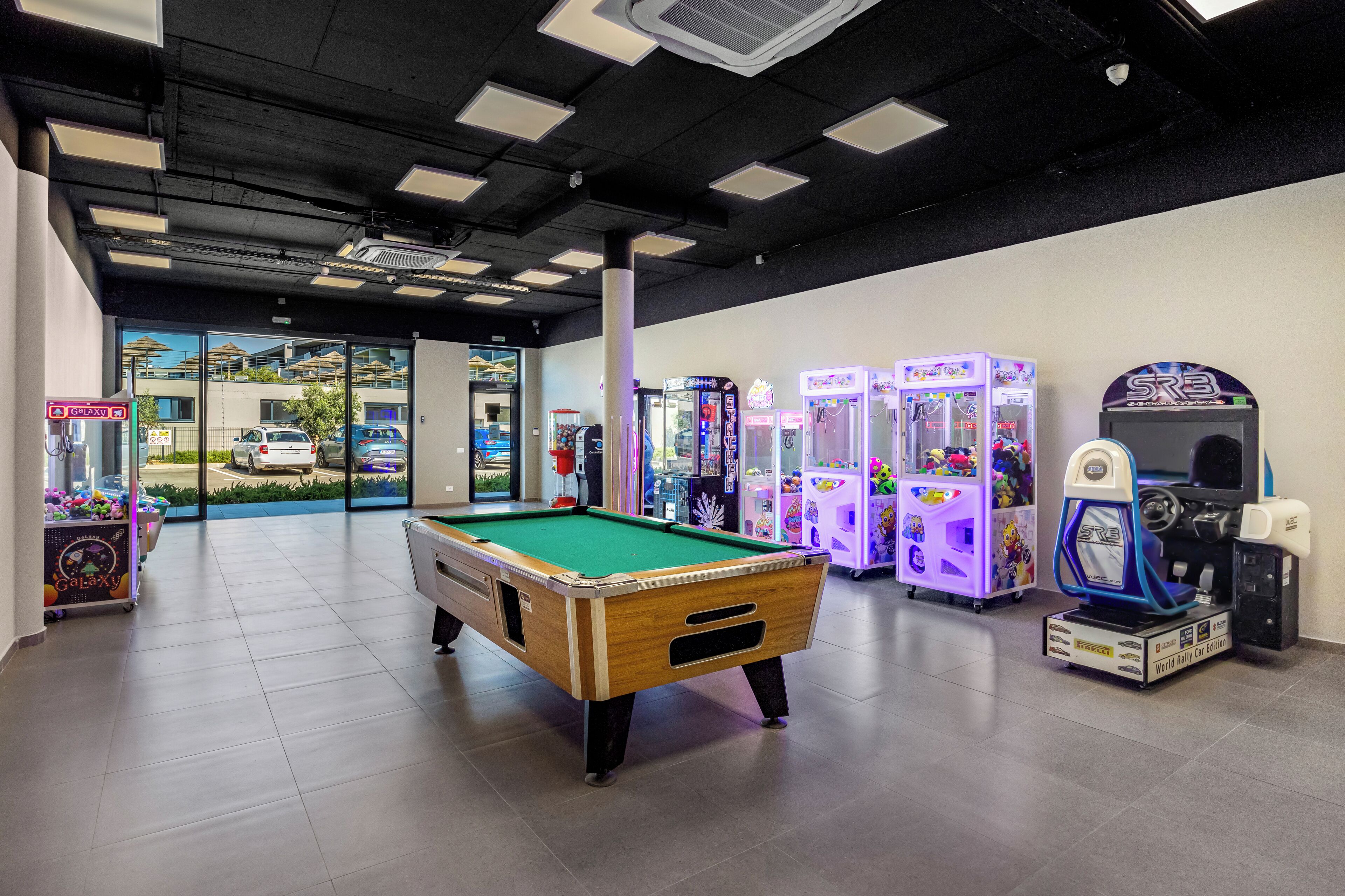 A pool table in a room with arcade games and a Galaxy vending machine.