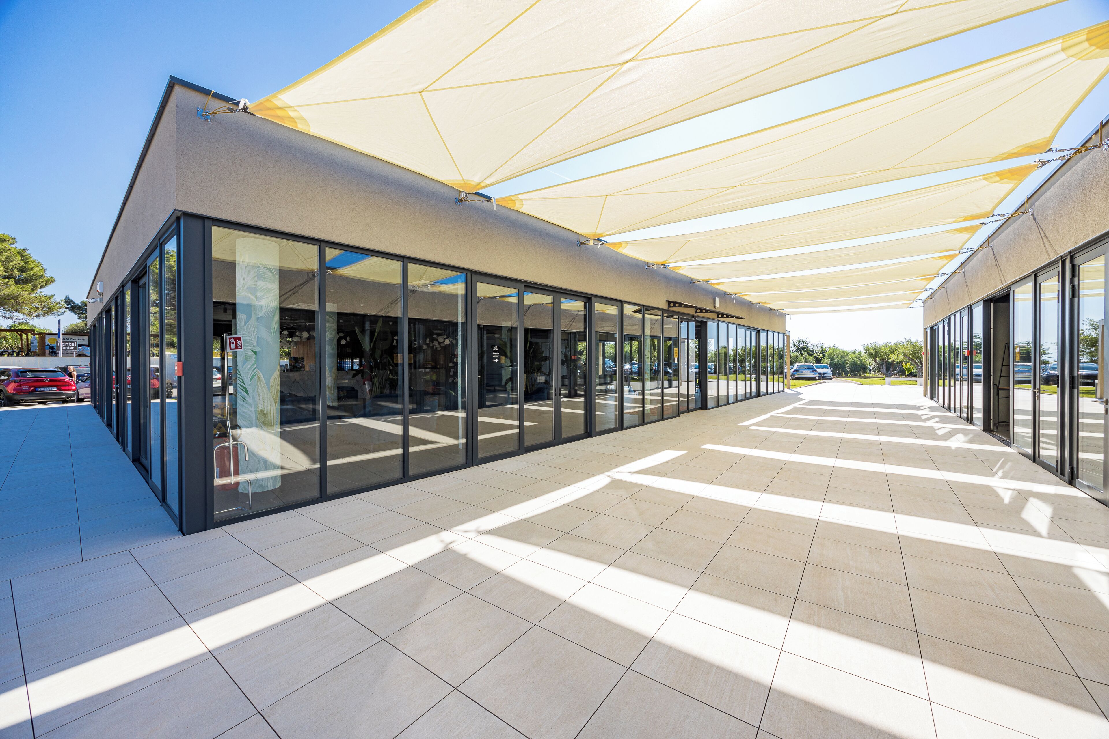 A modern building with large glass windows and a covered walkway.