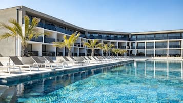 Relax by the pool surrounded by palm trees and lounge chairs, with expansive views from the hotel's contemporary design.
