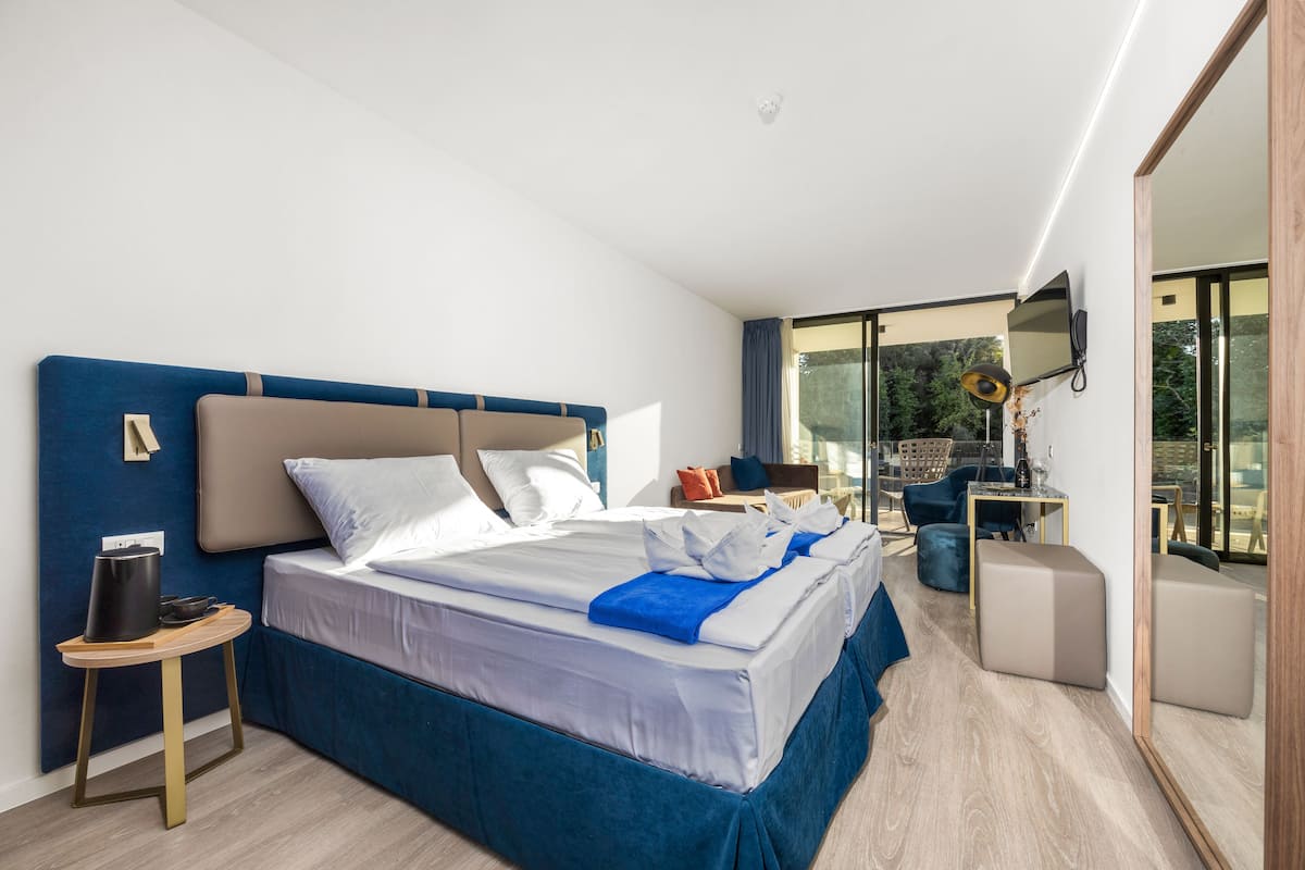 A modern hotel room with a large bed, a desk, and a TV mounted on the wall.