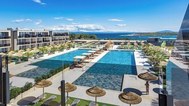 Un resort con diverse piscine, zone relax e vista sul mare.