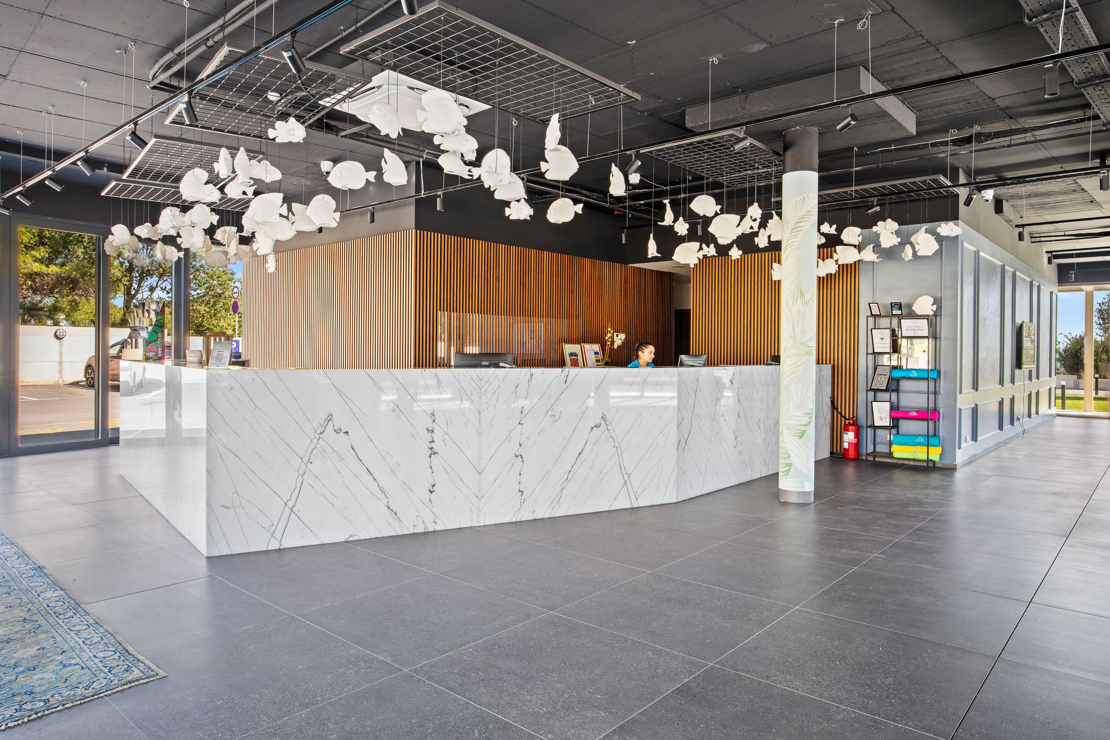 A modern reception area with a marble counter, hanging light fixtures, and a wooden panel wall.