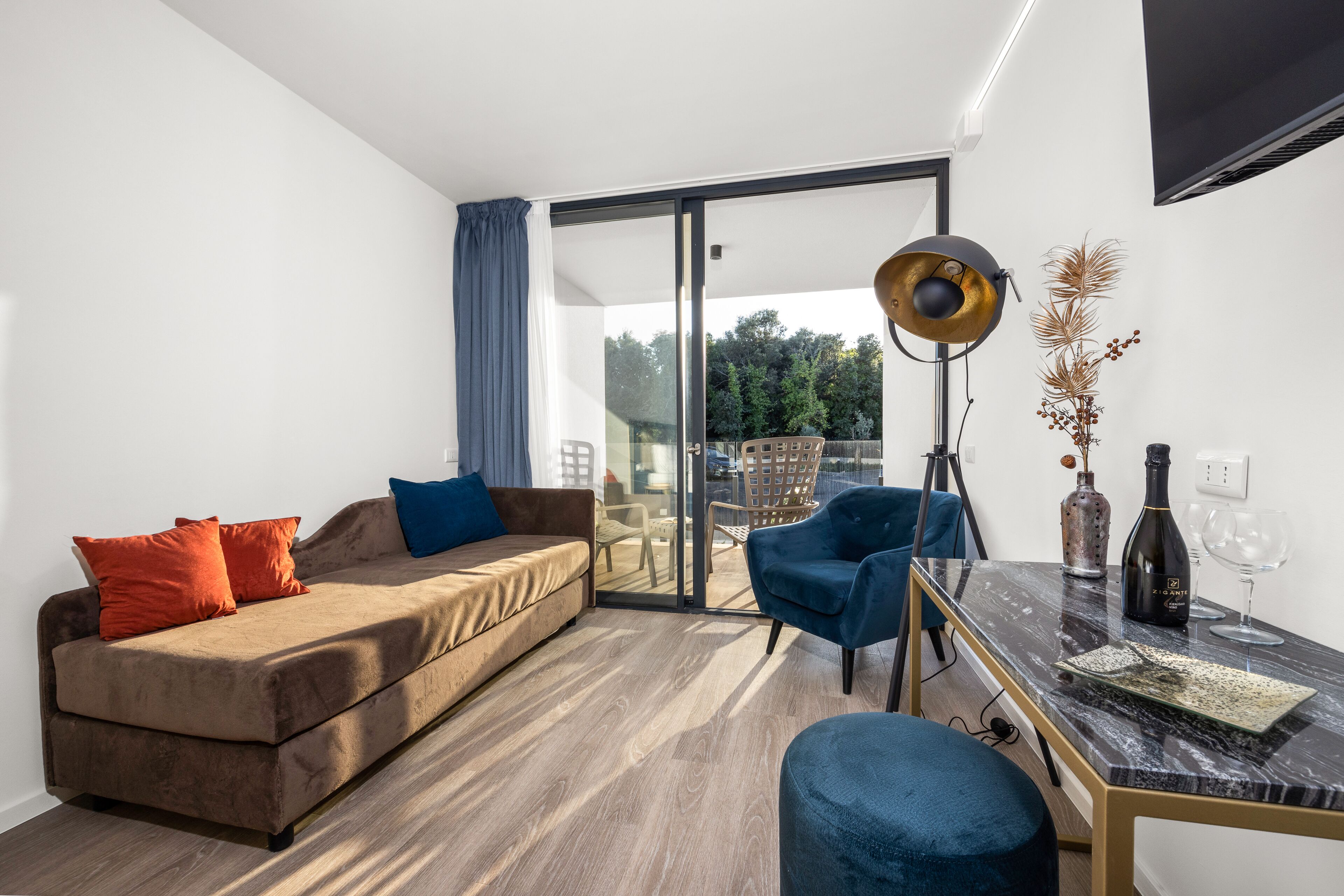Een moderne woonkamer met een bank, stoelen, een tafel en een groot raam.
