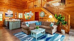A cozy cabin interior with a wooden staircase, a dining area, and a living room with a sofa and coffee table. - A Smoky Mountain Lake Cabin, Spacious Smoky Mountain Getaway, Free Tickets! (Sevierville)