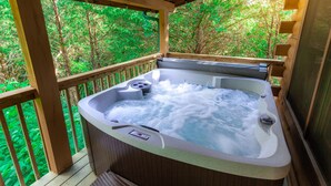 A hot tub on a wooden deck with a view of green trees. - A Smoky Mountain Lake Cabin, Spacious Smoky Mountain Getaway, Free Tickets! (Sevierville)
