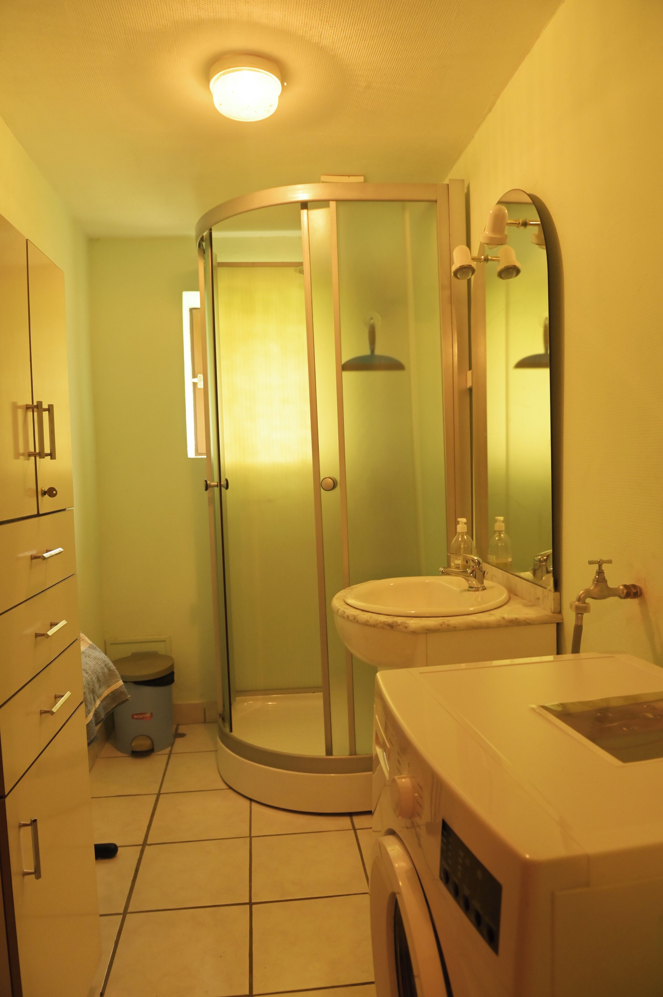 A bathroom with a glass-enclosed shower, a sink, and a mirror.