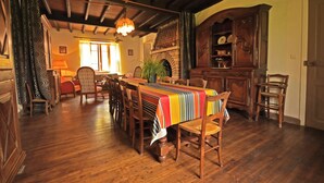 Un coin repas avec une table et des chaises en bois, une nappe à motifs et une cheminée traditionnelle.