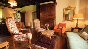 Un salon chaleureux avec des meubles en bois, un fauteuil à motifs, une table basse ronde et un canapé vert.