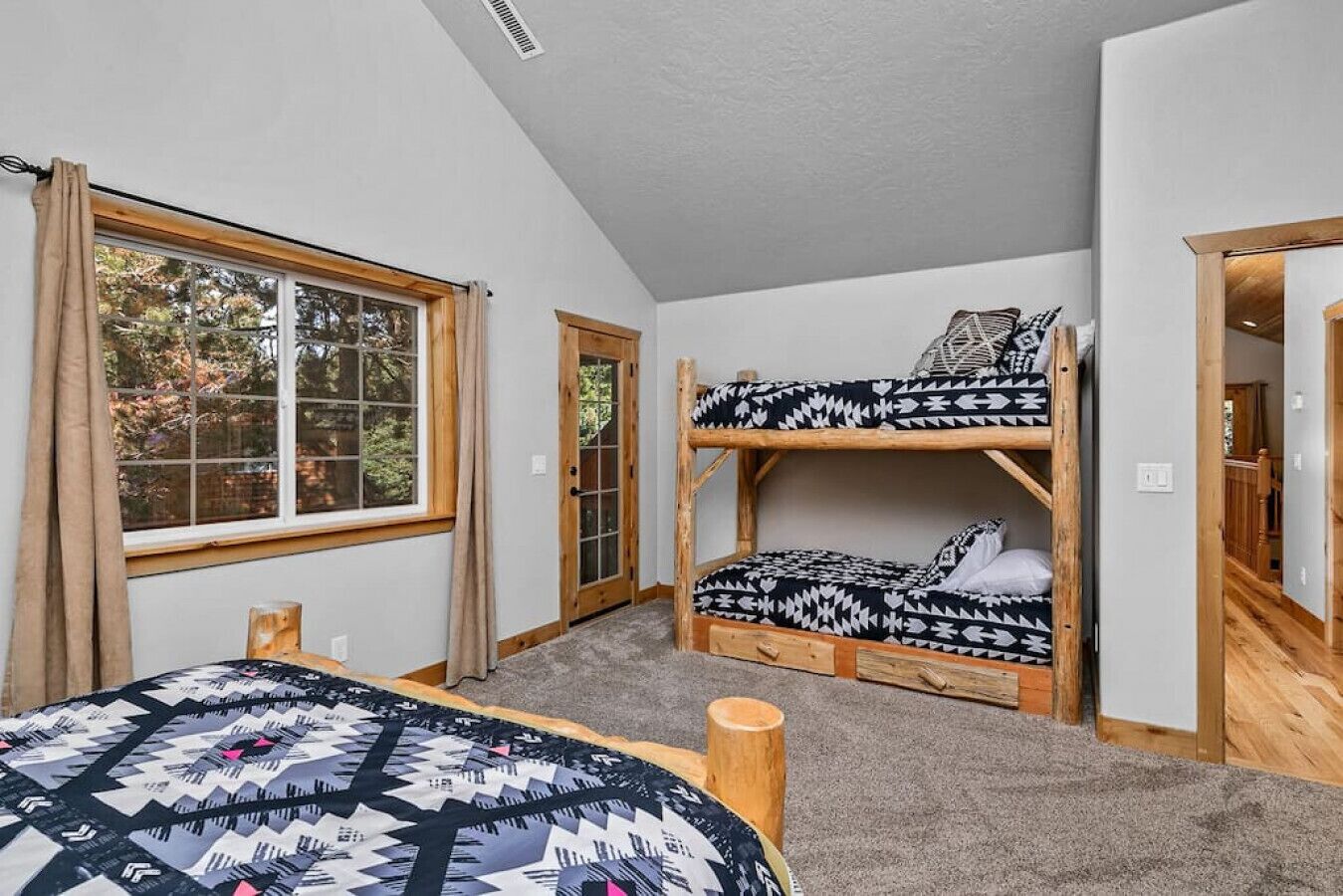 A room with two bunk beds, a window with curtains, and a door.