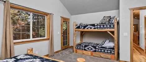 A room with two bunk beds, a window with curtains, and a door.