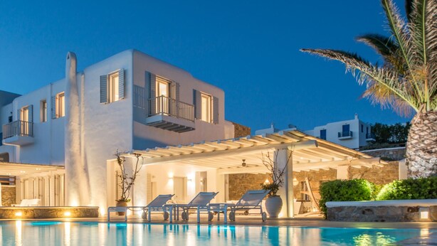 A modern villa with a pool, outdoor seating, and a well-lit patio area.