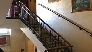 Un intérieur à plusieurs niveaux, doté d’un escalier orné de rampes en métal ouvragé et de mains courantes en bois.